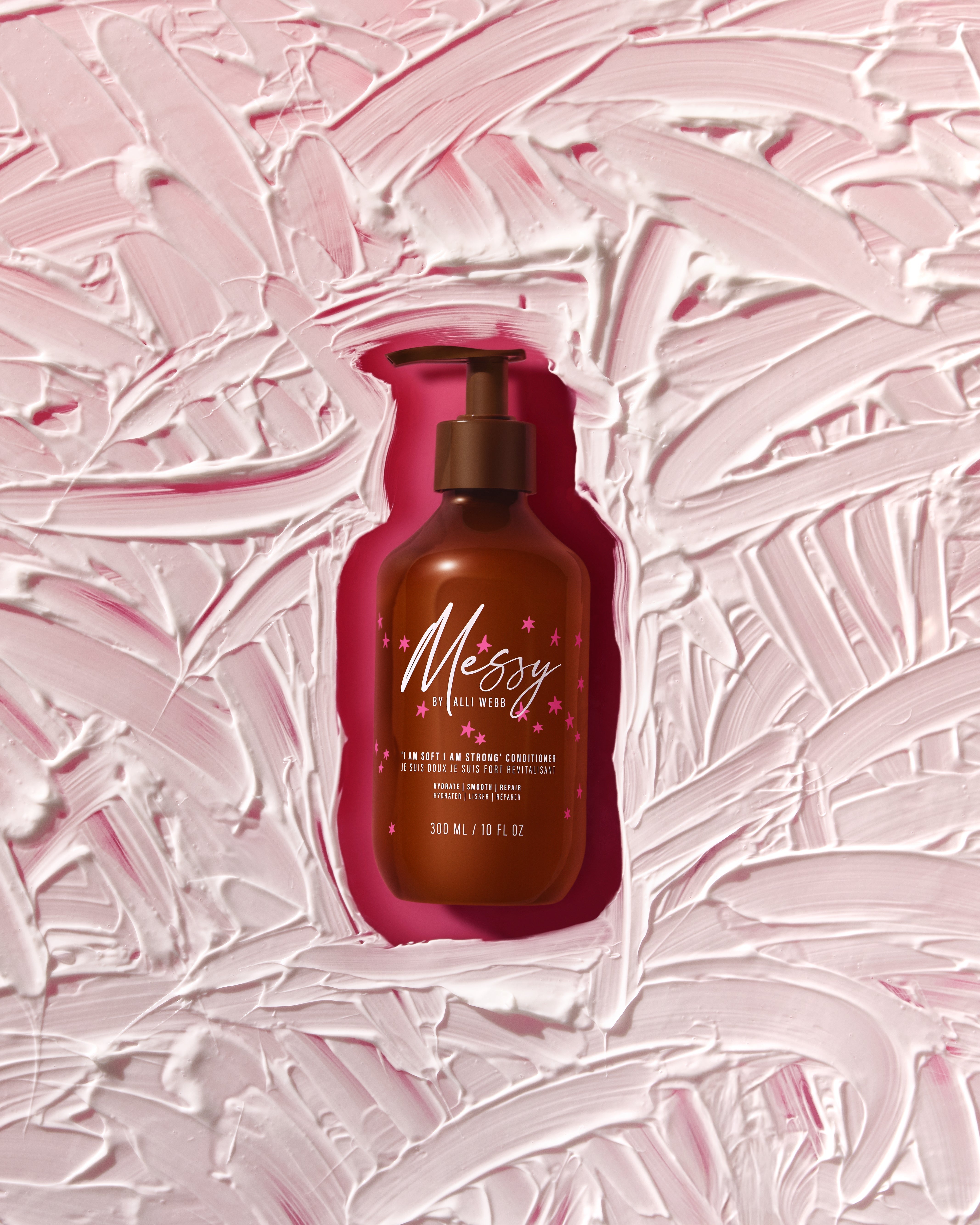 Conditioner bottle nestled in swirls of soft pink cream.