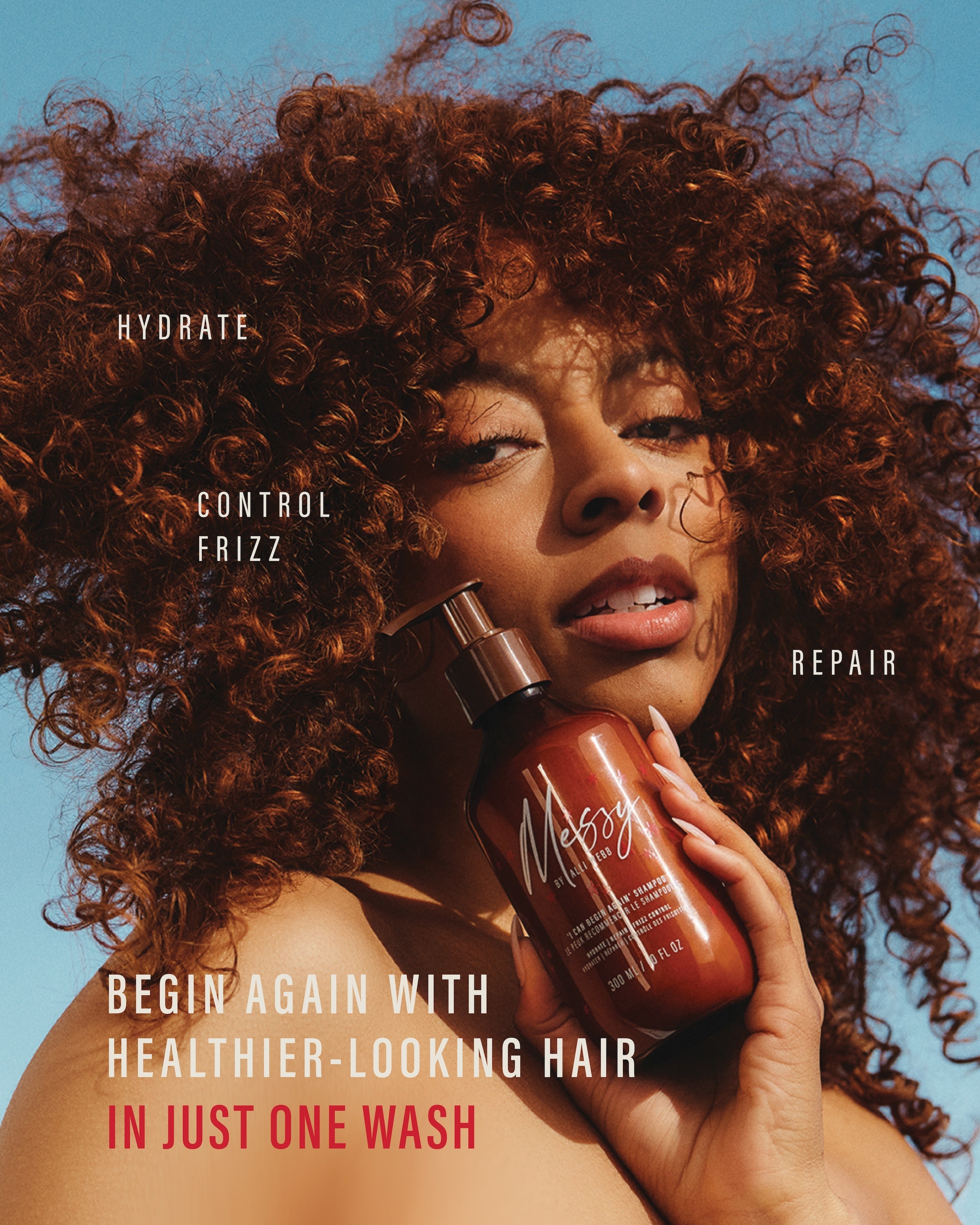 Model with voluminous curls holds the Shampoo — hydrate, control frizz, repair: healthier-looking hair in just one wash.